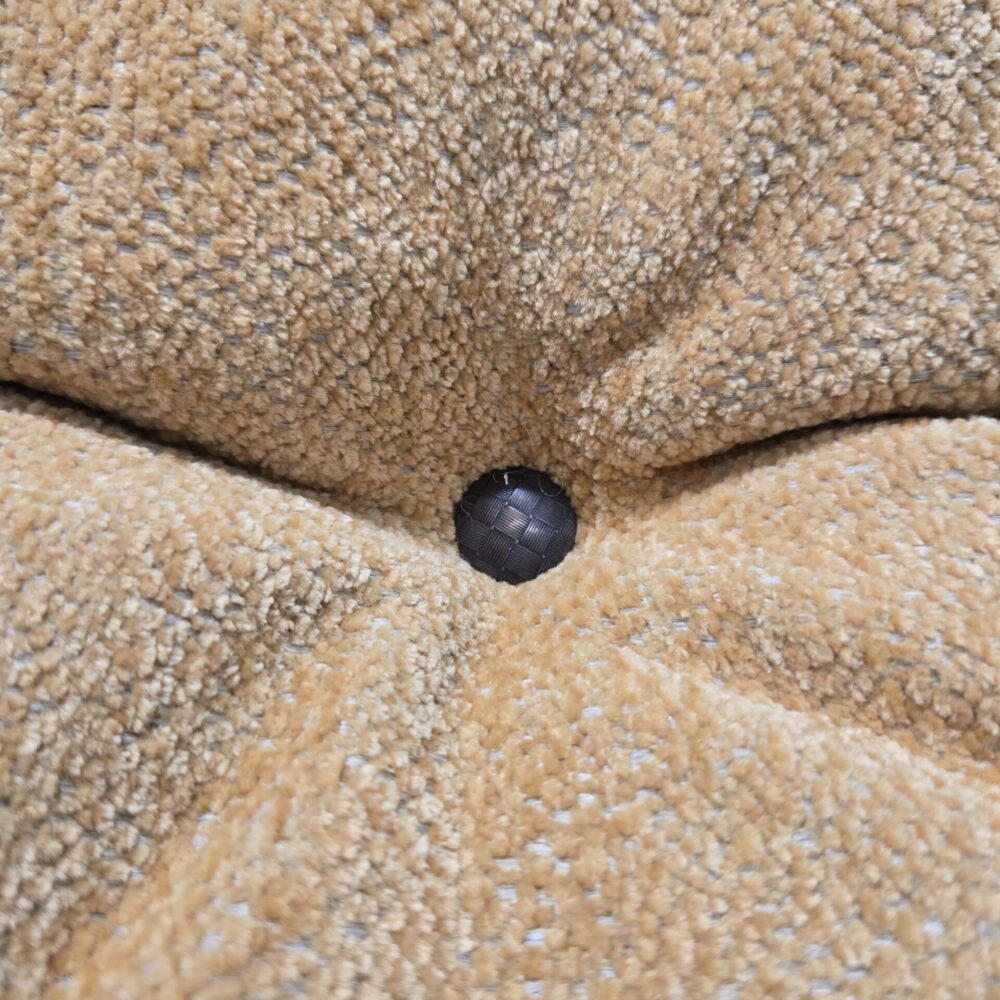 Gros plan sur un capiton noir tissé dans un tissu d'ameublement en velours bouclé ou chenille beige/moutarde.