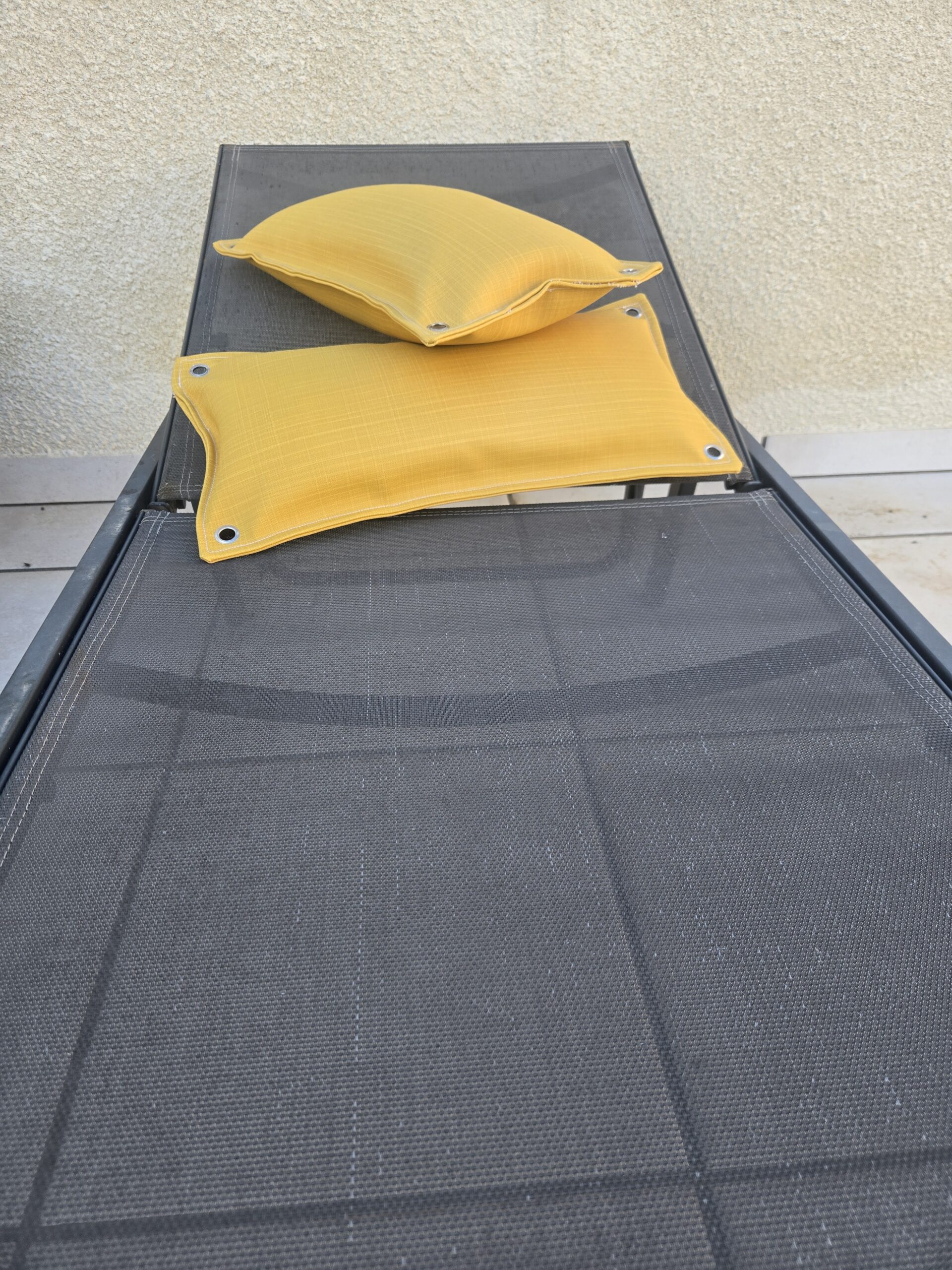 vue de face de 2 coussins en tissu bateau jaune safran finition œillets aux angles