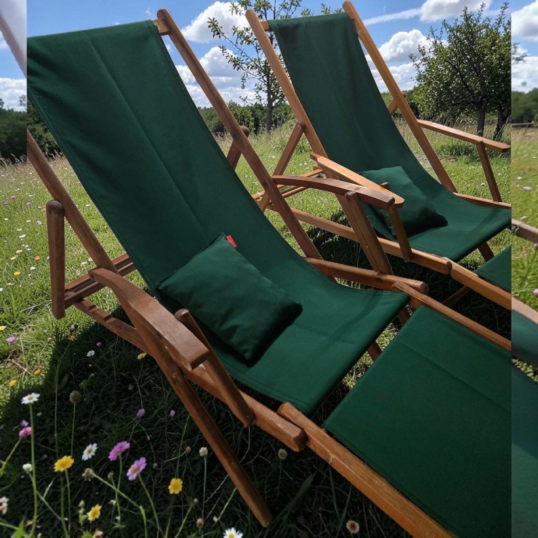 2 chiliennes anciennes en teck avec repose pied, et un tissu outdoor vert bouteille dans un décor de prairie en fleurs et ces coussins repose tête assortis